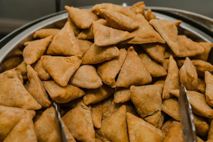 Close-up of a large batch of crispy golden samosas in a serving dish, ready to be enjoyed.
